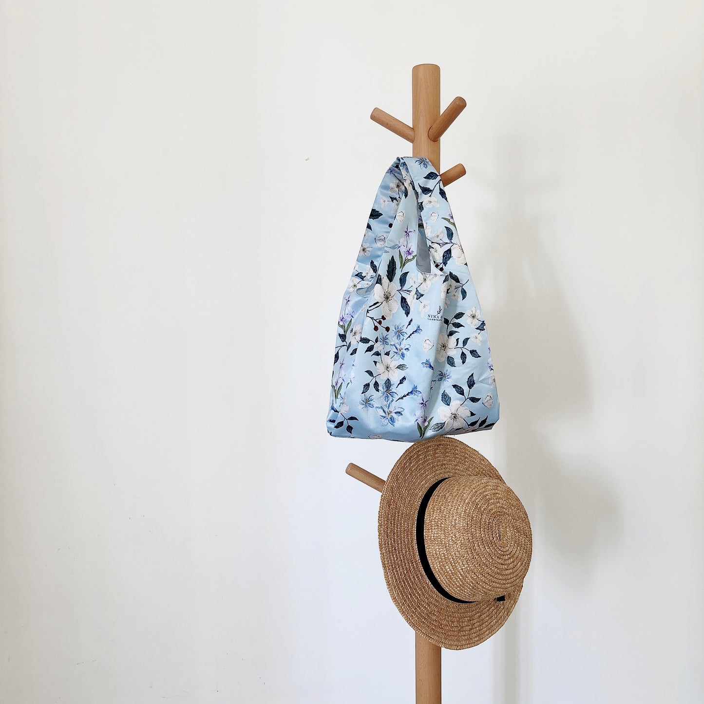Floral wander reusable bag hanging on a hanger, satin fabric with original watercolor floral prints, reflecting a natural and elegant lifestyle.