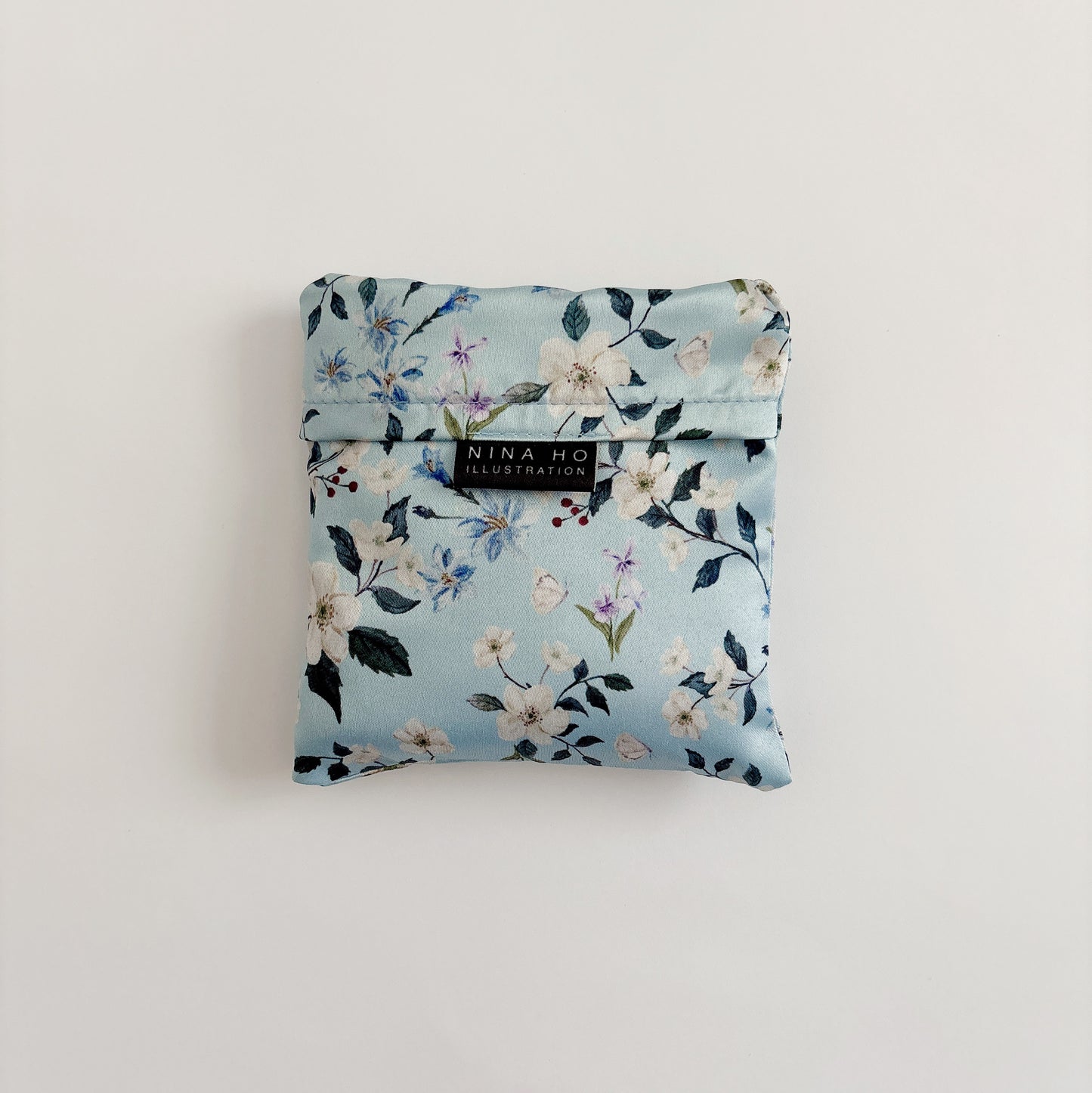 Floral wander reusable bag fully folded, showcasing its lightweight texture and elegant floral prints.