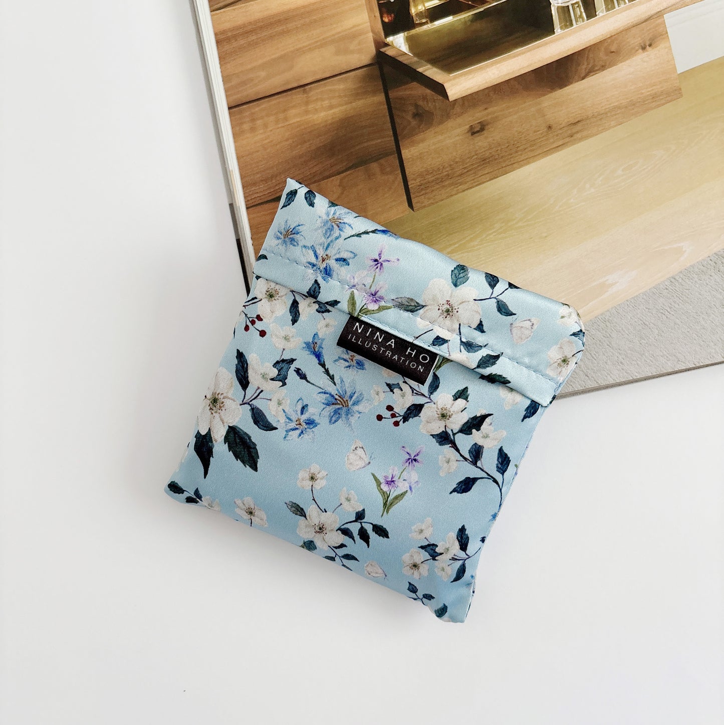 Floral wander reusable bag fully folded, showcasing its lightweight texture and elegant floral prints.