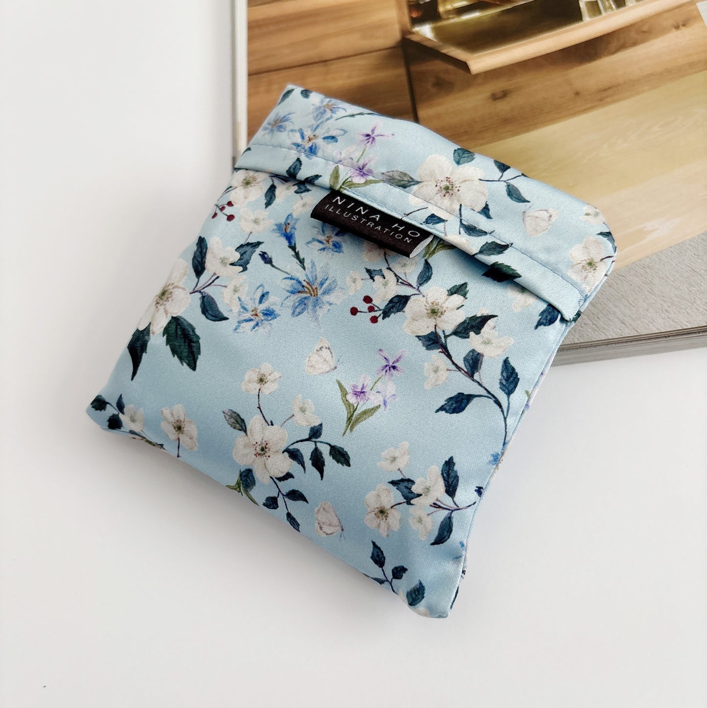 Floral wander reusable bag fully folded, showcasing its lightweight texture and detail of floral prints.
