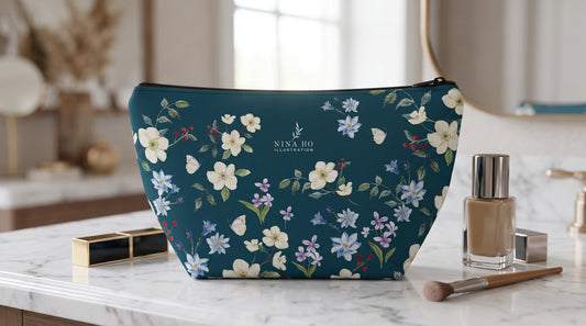 Deep blue-green waterproof canvas makeup bag adorned with delicate hand-painted Taiwanese high mountain rose, Alishan gentian, and arrowleaf violet floral motifs by NINA HO ILLUSTRATION, embodying botanical elegance and Parisian refined charm.