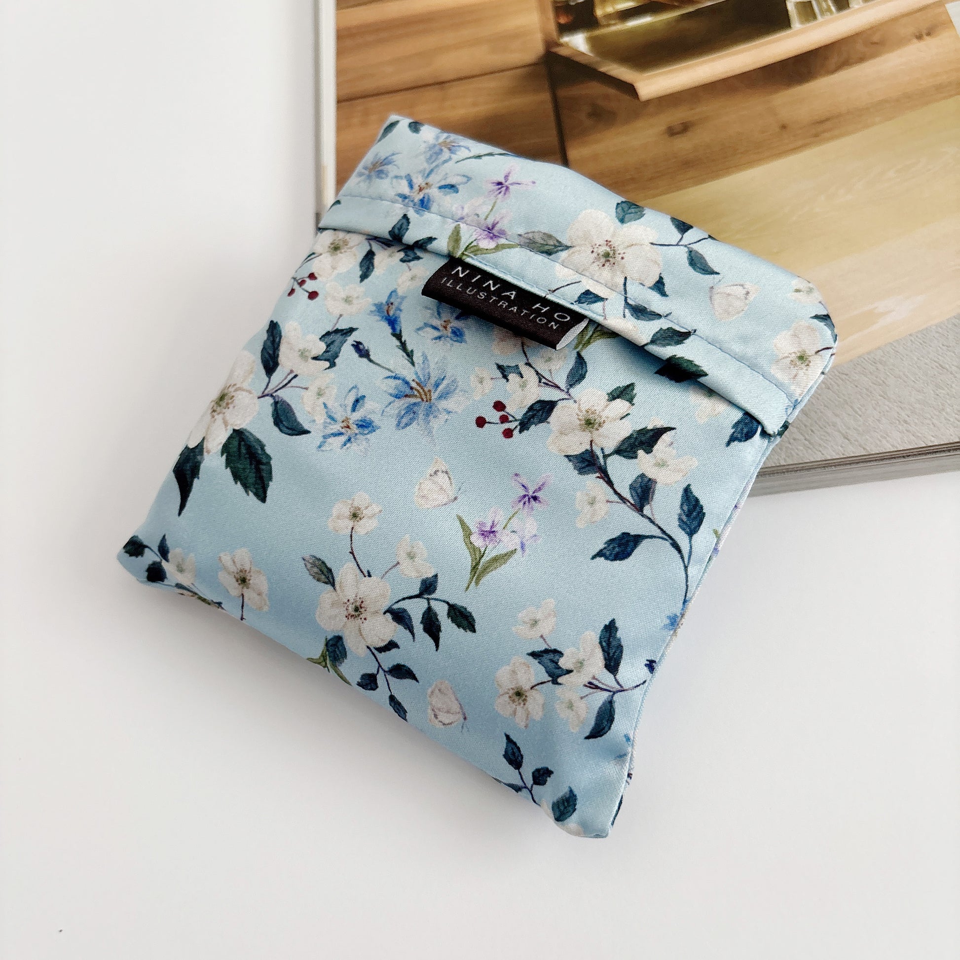 Floral wander reusable bag fully folded, showcasing its lightweight texture and detail of floral prints.