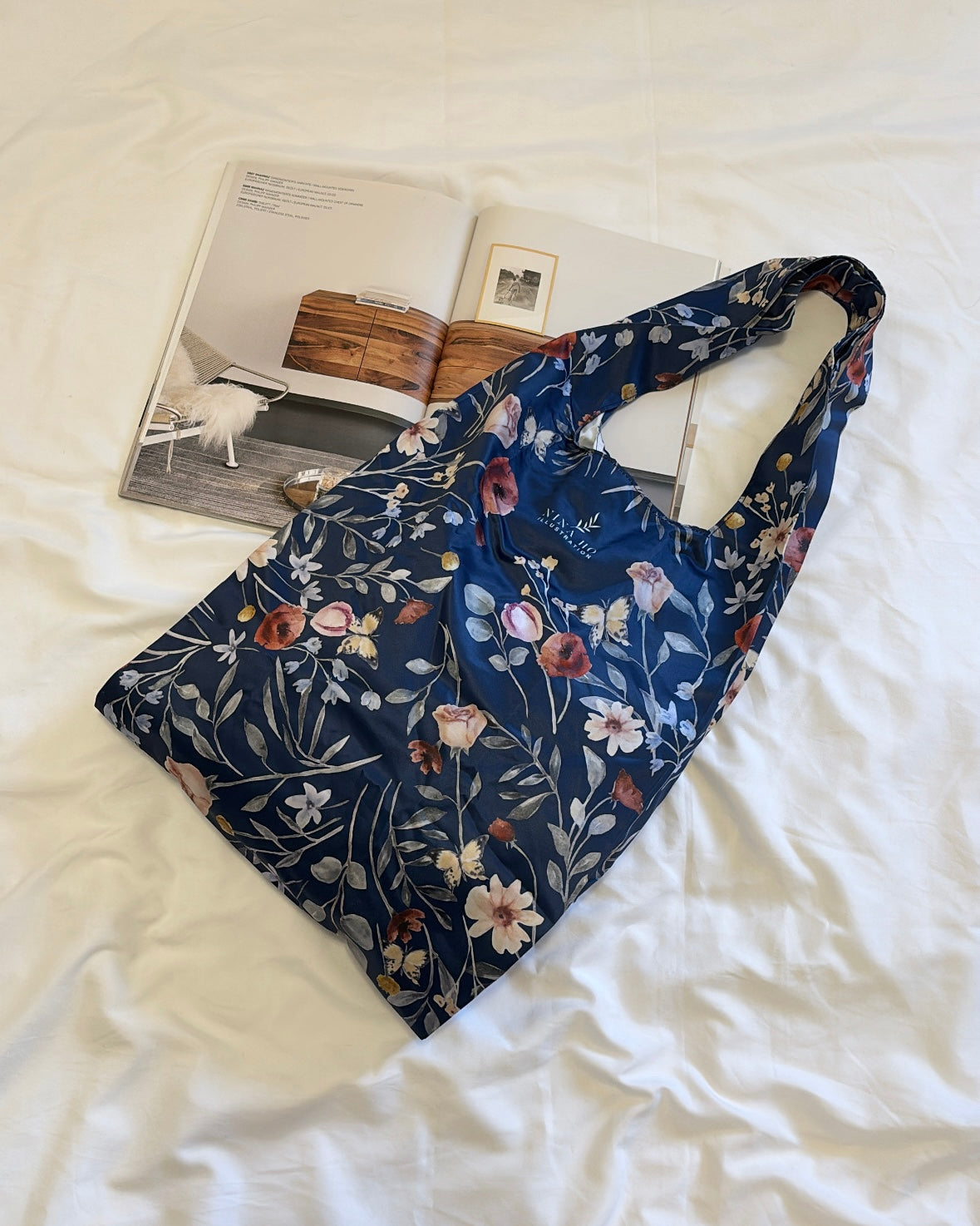 A refined deep blue botanical tote adorned with hand-painted illustrations of delicate poppies and subtle blossoms by NINA HO ILLUSTRATION, embodying Parisian chic and thoughtful artistry.
