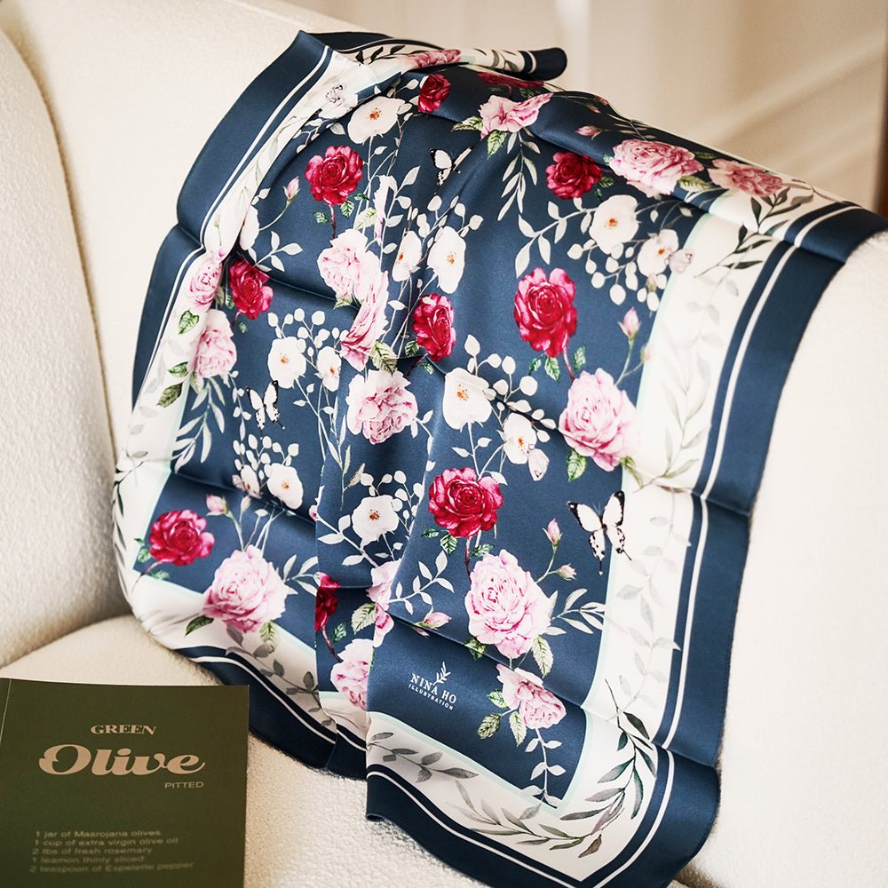 Deep teal silk scarf by Nina Ho Illustration with hand-painted floral motifs of garden roses and delicate blossoms, embodying Parisian chic.